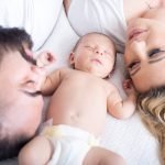 couple lying in bed with their newborn baby