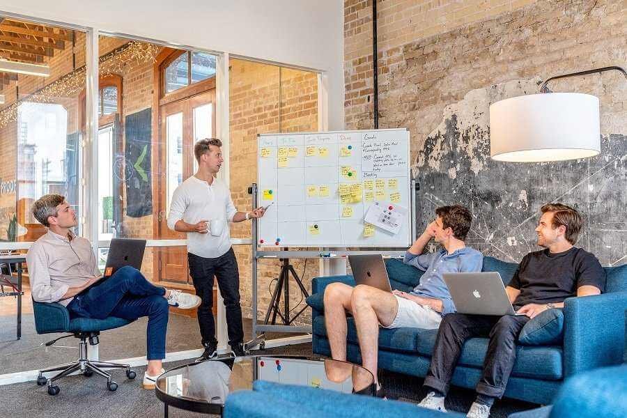 team of people discussing business plans laid out on a whiteboard