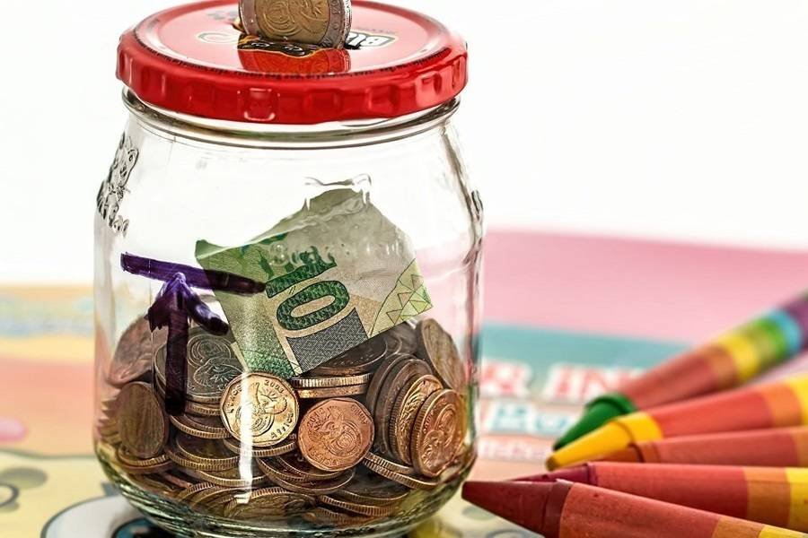 glass savings jar containing notes and coins